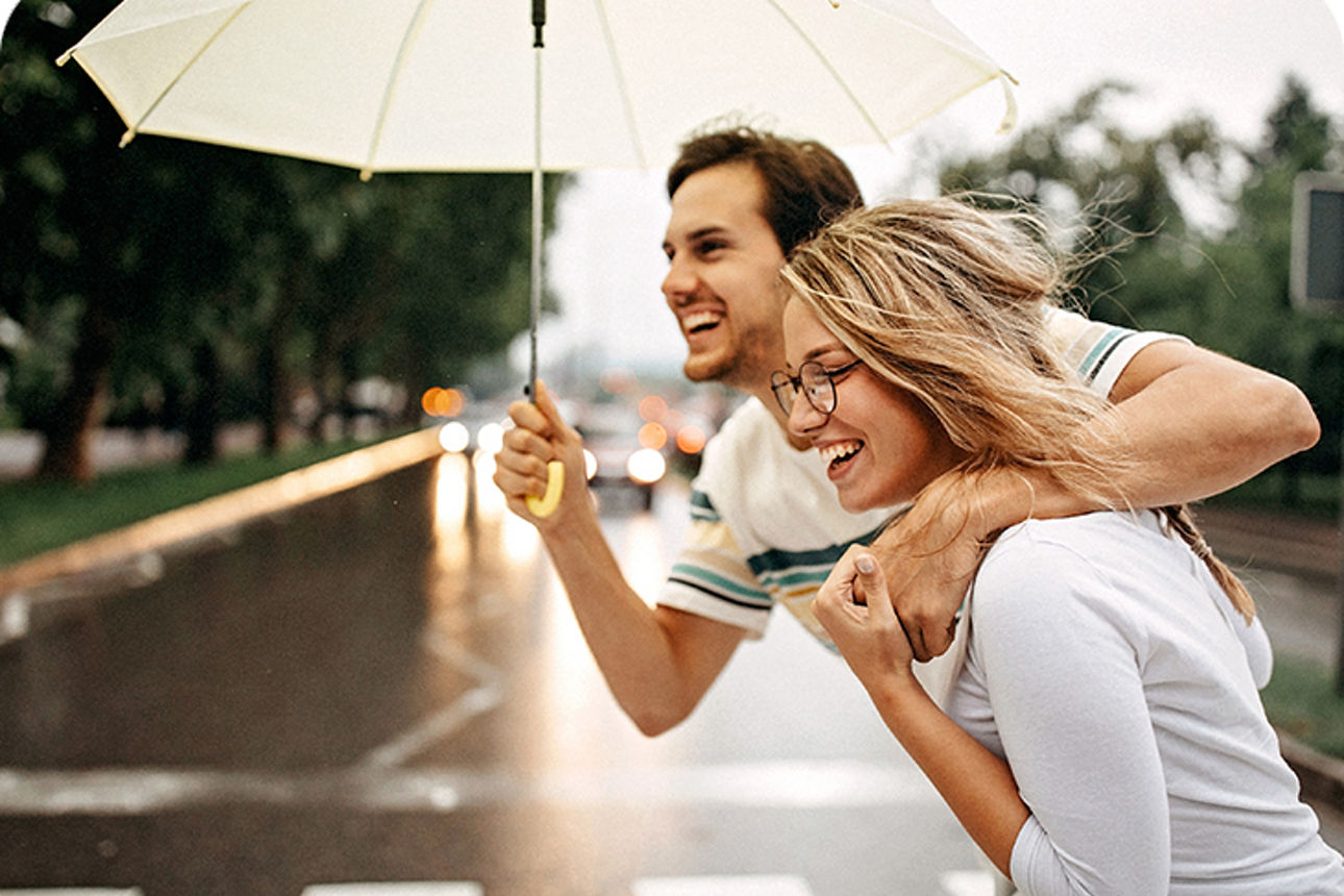 Paar läuft lachend bei Regen über eine Straße