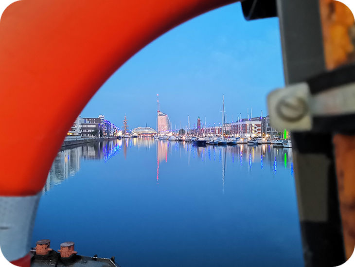 Hafen der Abends beleuchtet ist mit einer Stadt im Hintergrund