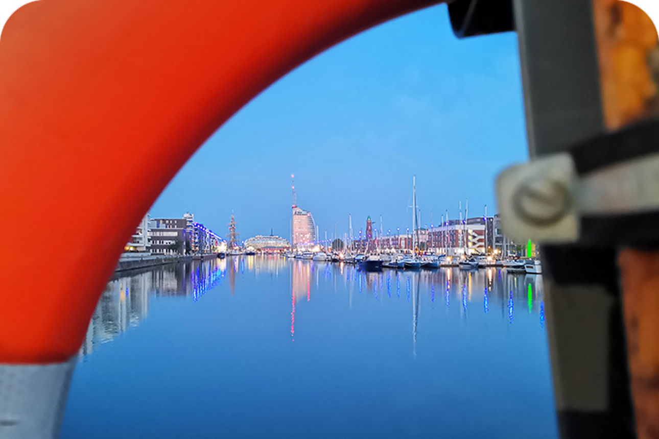 Hafen der Abends beleuchtet ist mit einer Stadt im Hintergrund