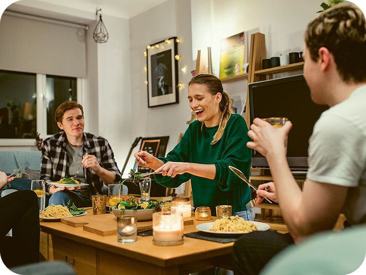 Drei Personen sitzen um einen gedeckten Tisch