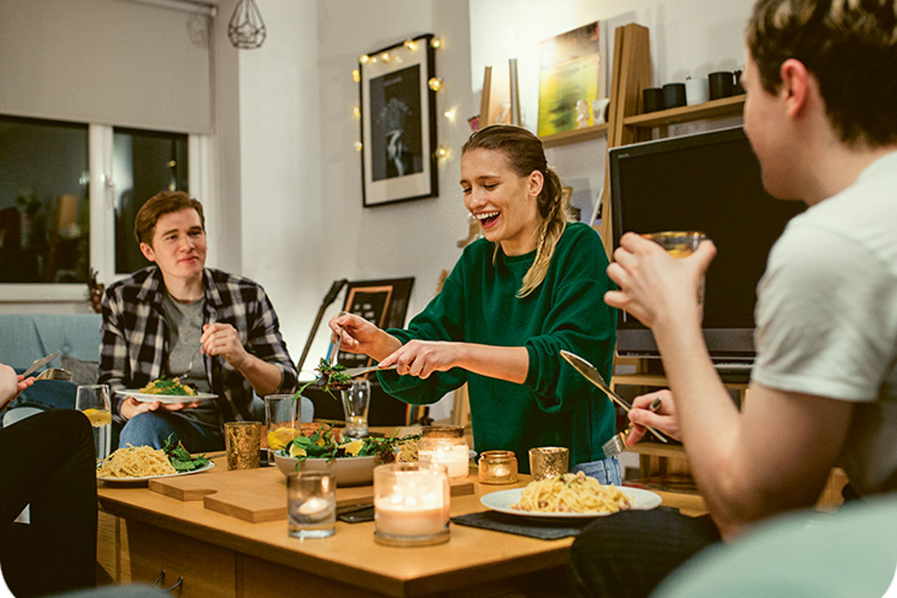 Drei Personen sitzen um einen gedeckten Tisch
