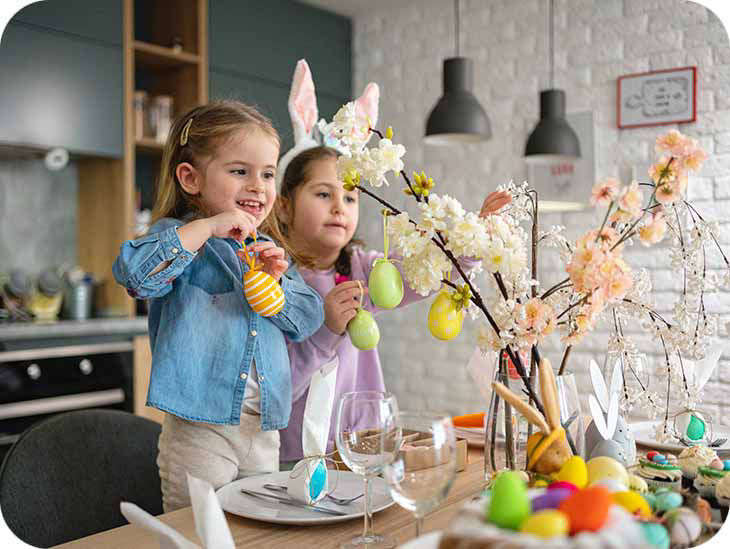 Zwei Kinder schmücken Äste mit Ostereiern
