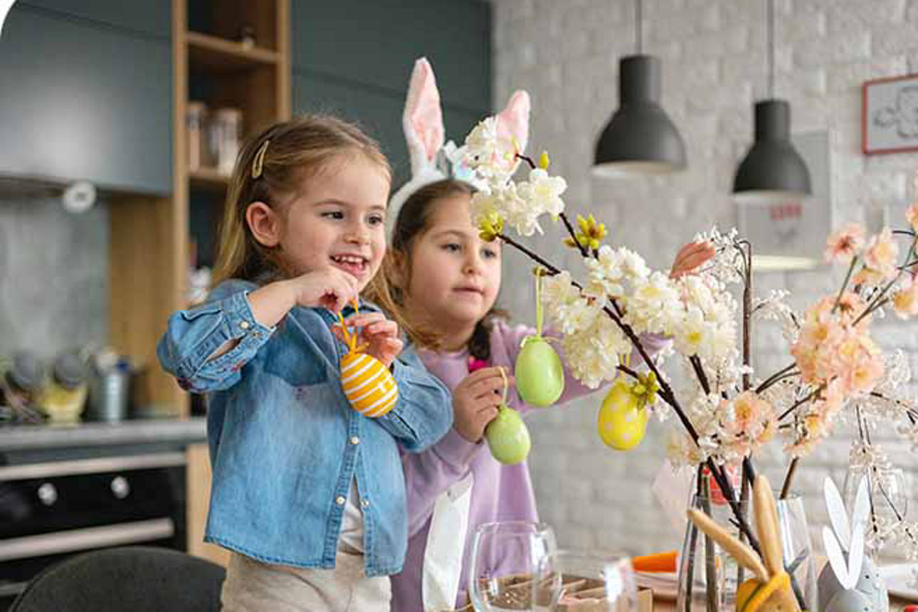 Zwei Kinder schmücken Äste mit Ostereiern