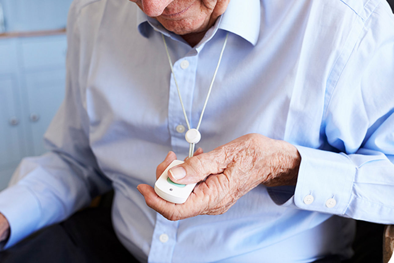 Älterer Mann hält einen Alarmknopf in der Hand
