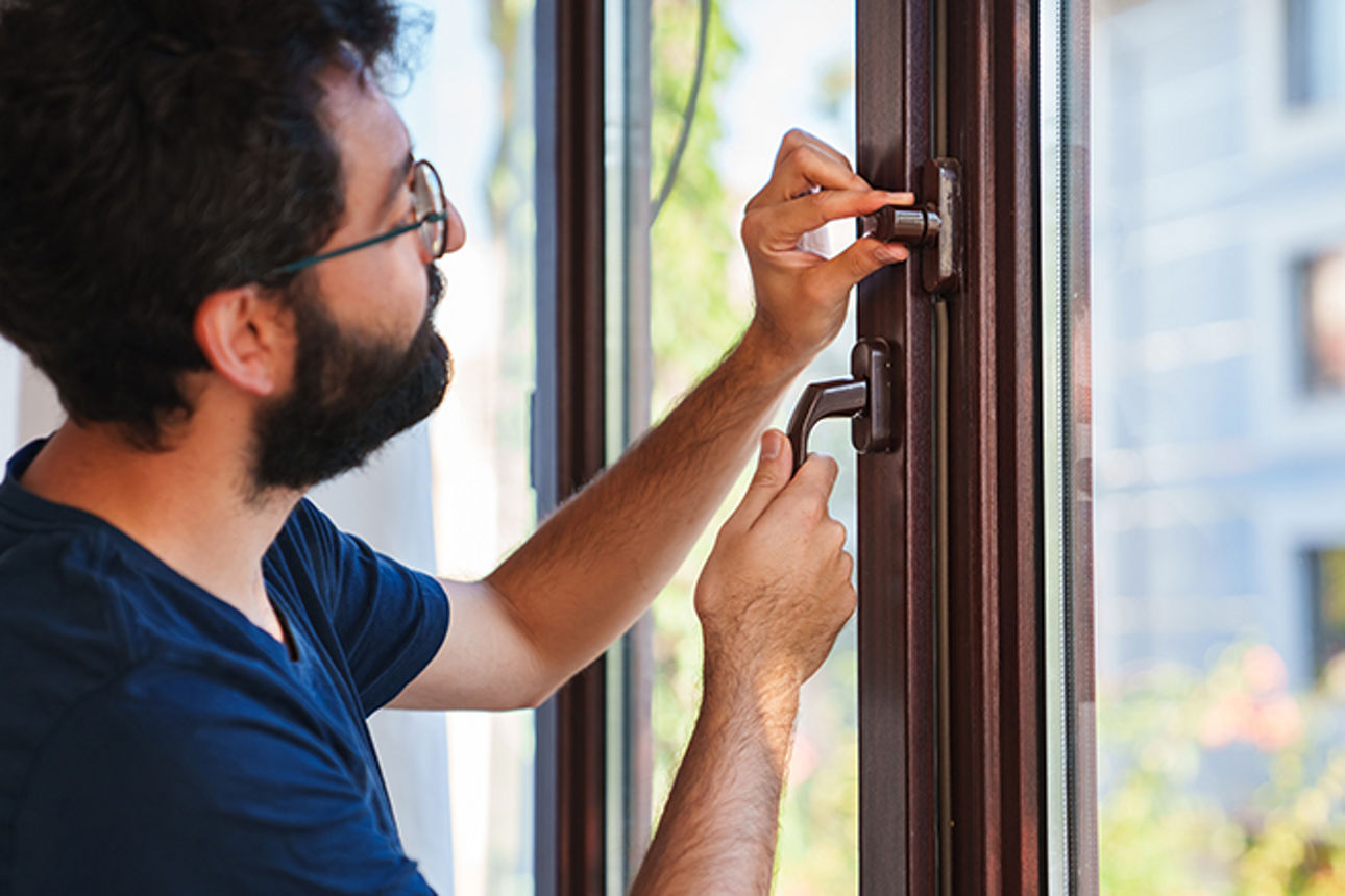 Mann macht ein Fenster Einbruchsicher