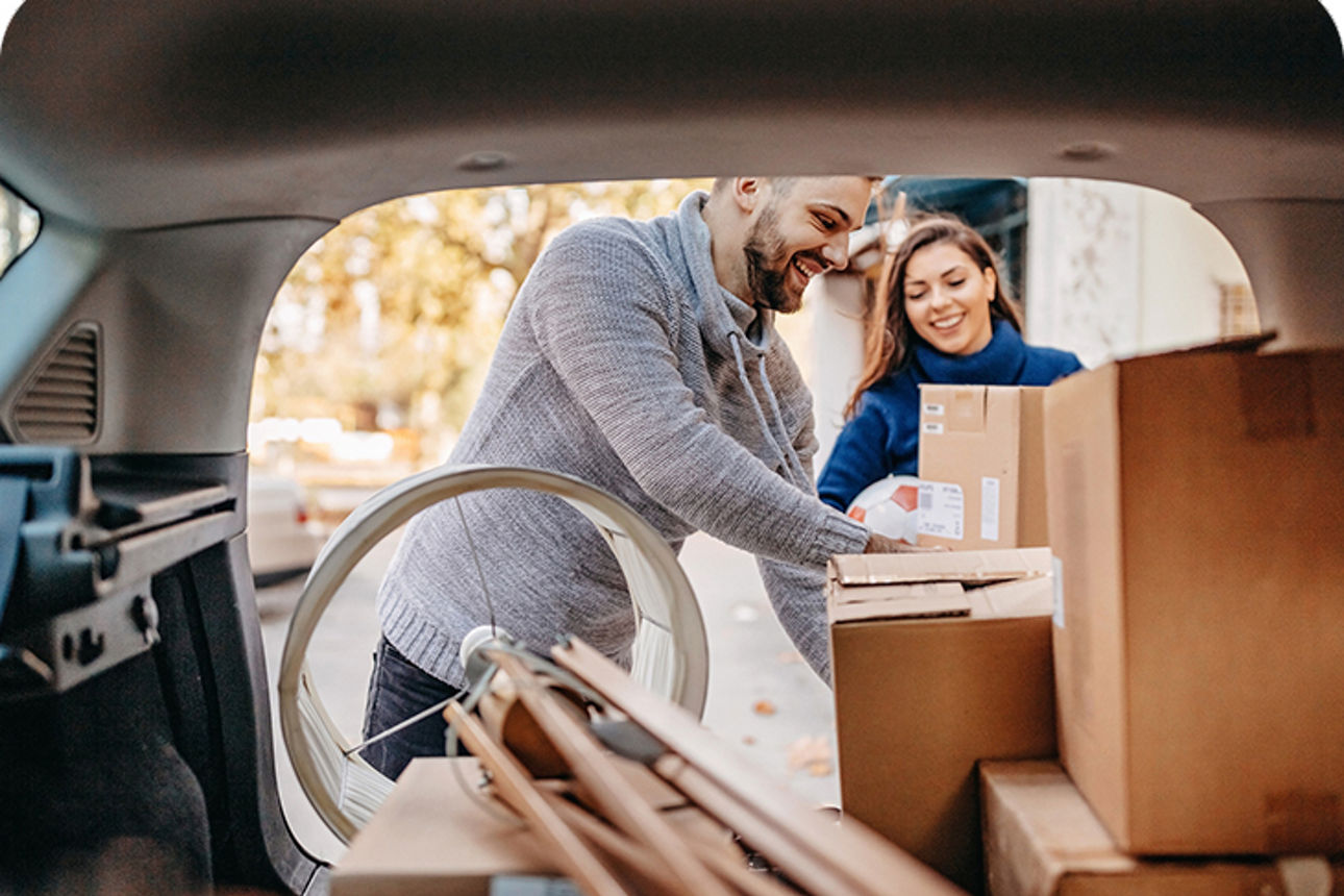 Paar packt eine Auto mit Umzugskartons
