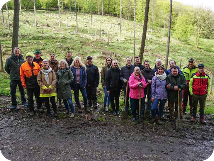 Eine Gruppe von Personen im Wald mit Setzlingen im Hintergrund