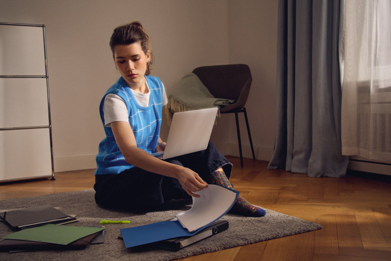 Eine Frau sitzt  mit Aktenordnern auf dem Boden 