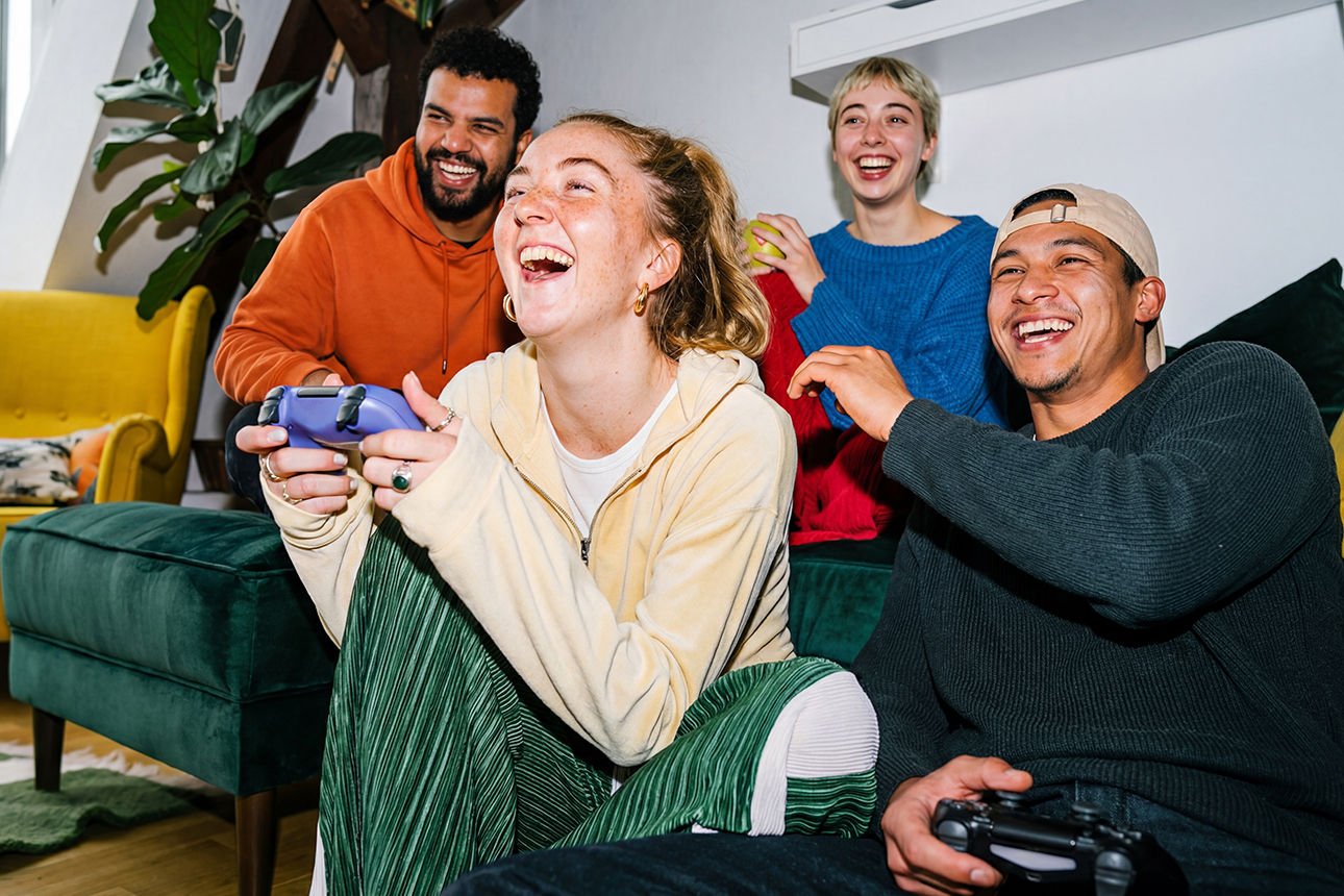 Freunde lachen beim gemeinsamen Videospiel im Wohnzimmer