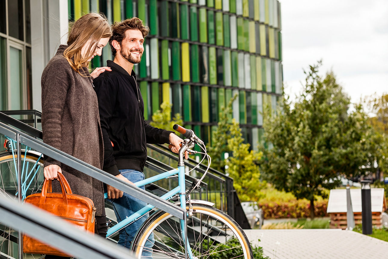 Paar schiebt Fahrrad durch modernes Wohnviertel