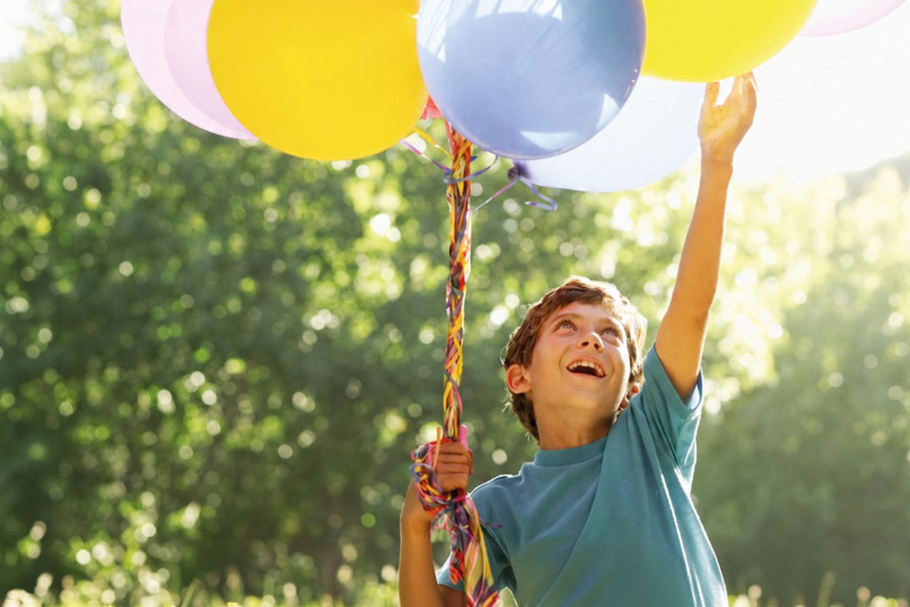 Junge hält ein Bündel Luftballons in der Hand