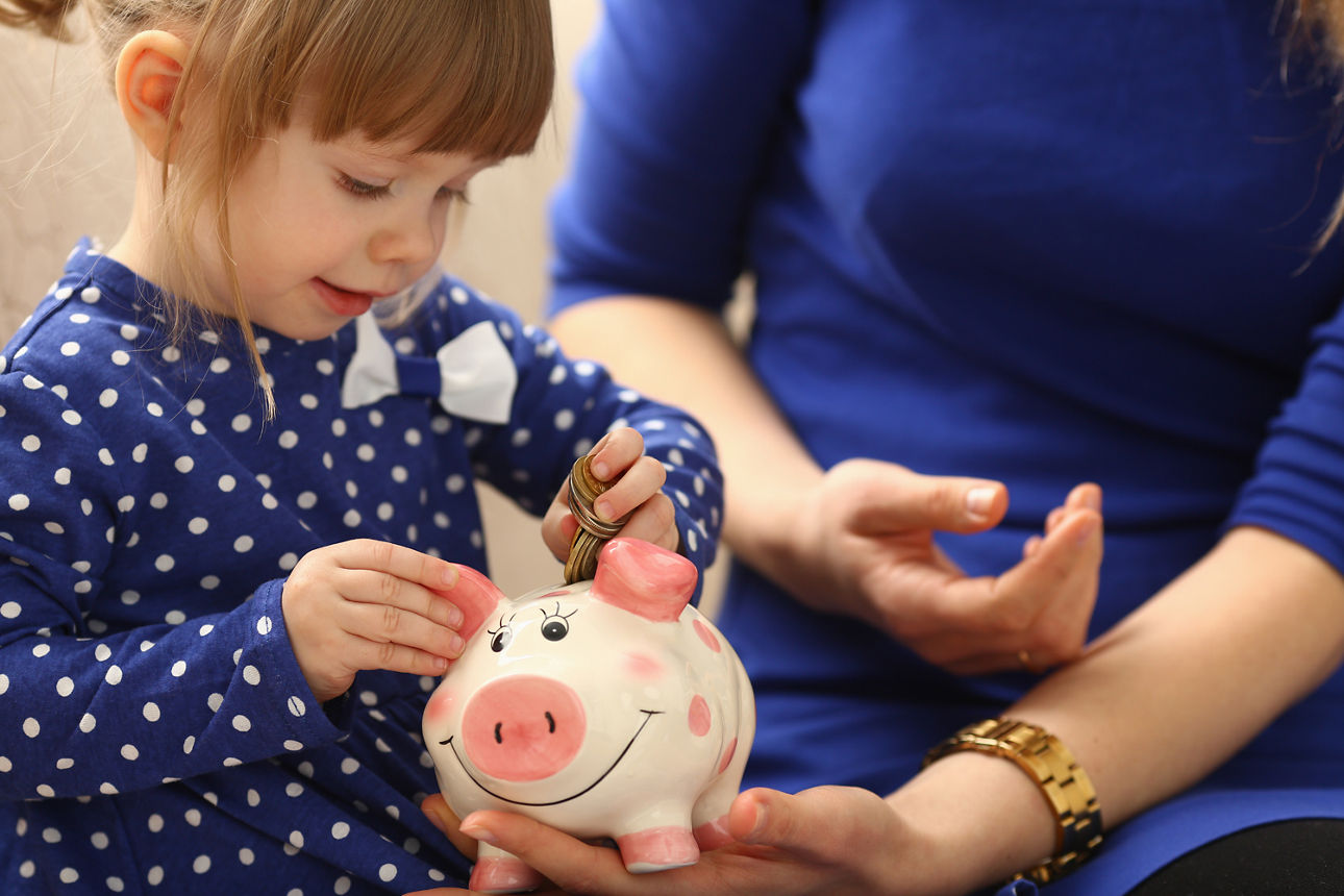 Mädchen steckt Geld in Sparschwein
