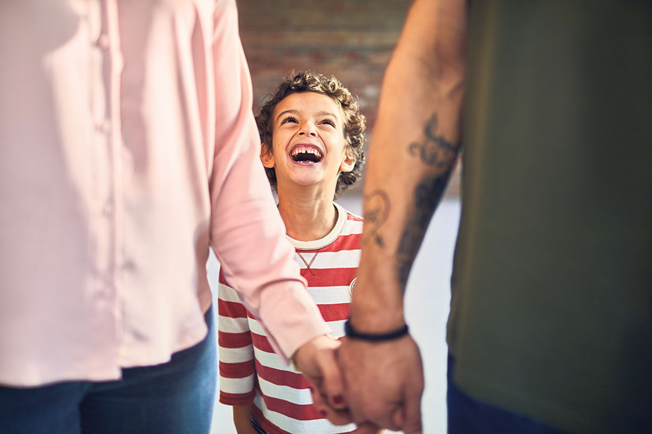 lachender Junge zwischen zwei Erwachsenen
