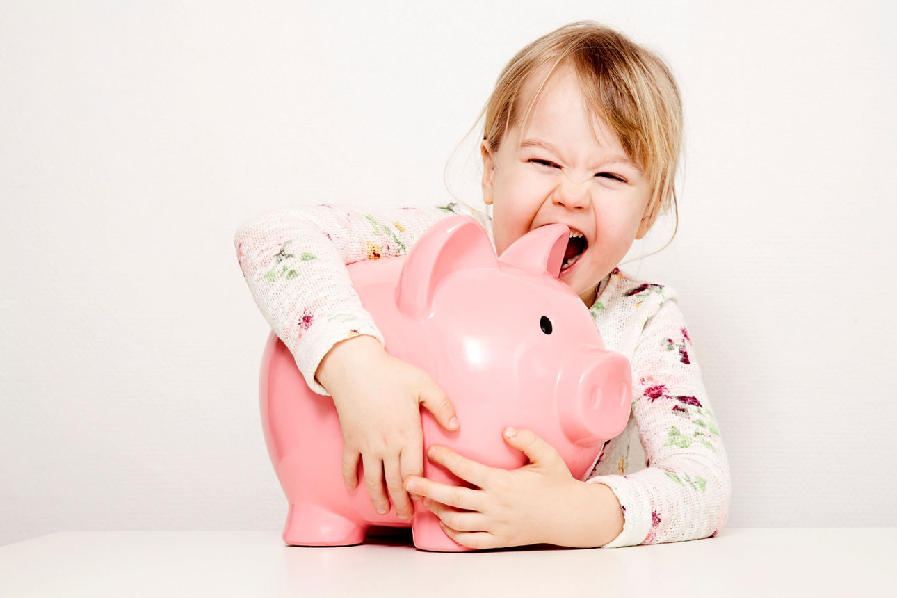 Kleines Mädchen umarmt Sparschwein