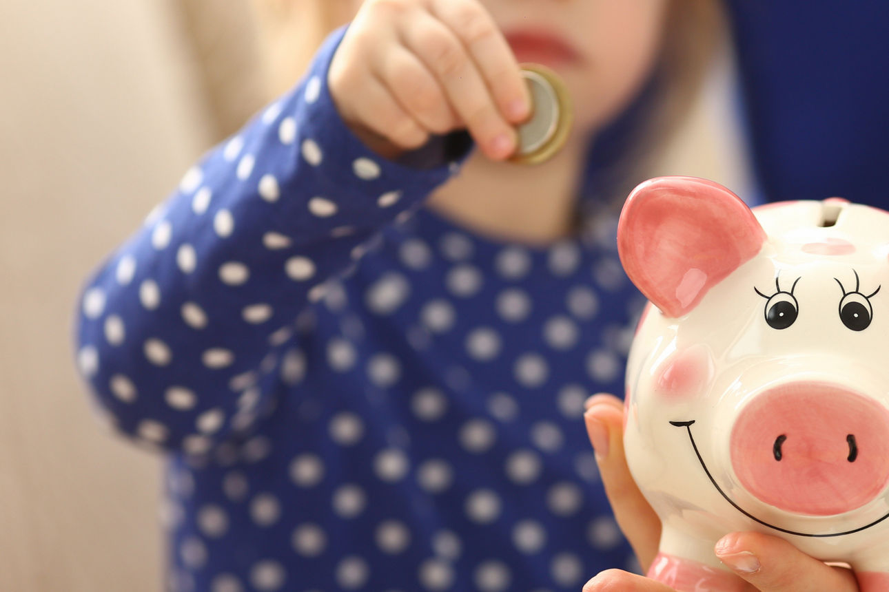 Kleines Mädchen steckt Geld in Sparschwein
