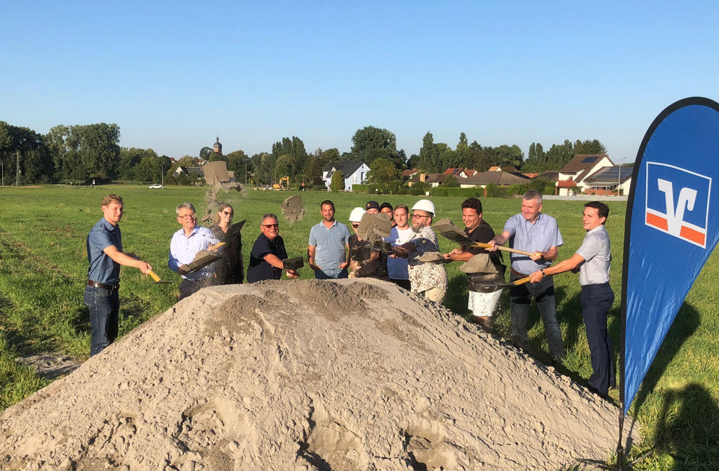 Einige Menschen stehen hinter einem Berg aus Sand und schaufeln weiter Sand darauf