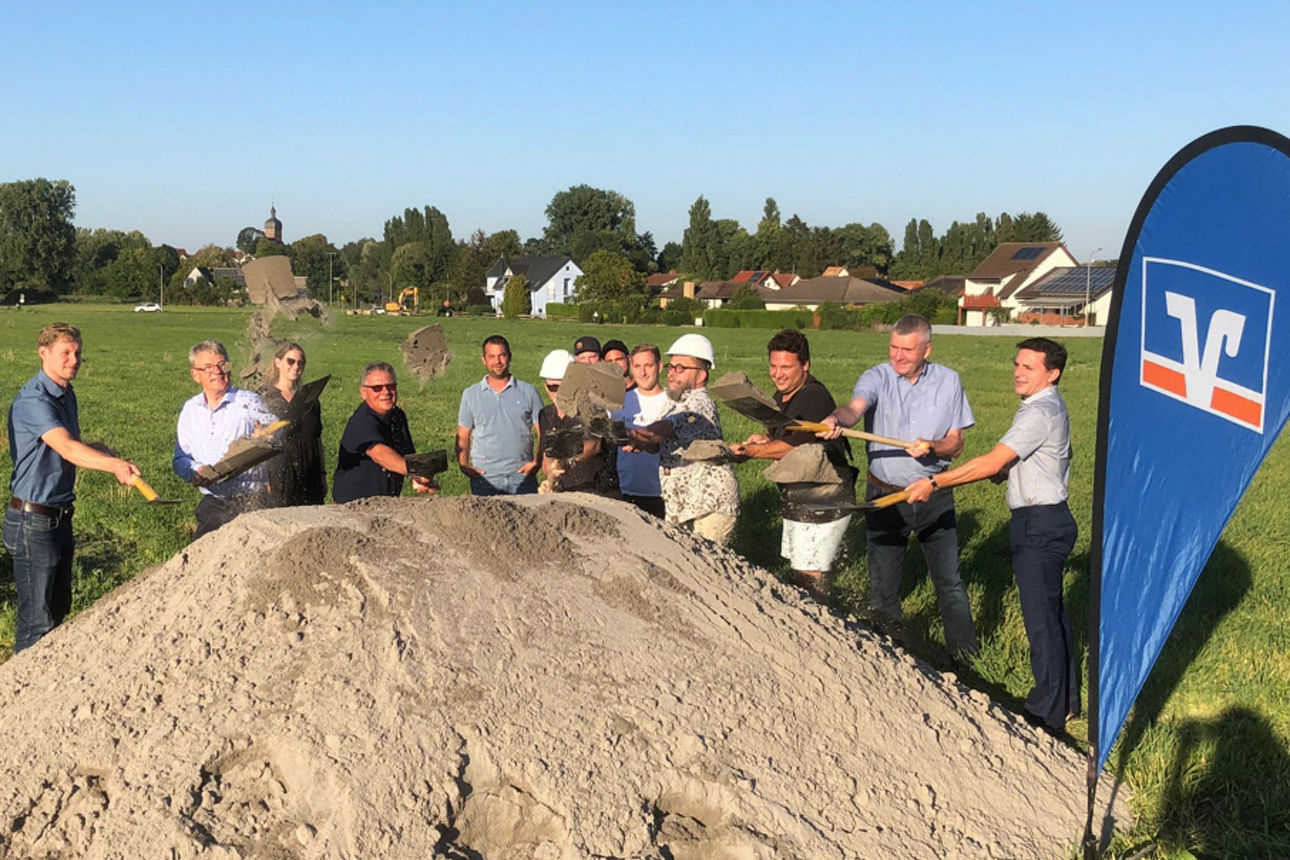 Einige Menschen stehen hinter einem Berg aus Sand und schaufeln weiter Sand darauf