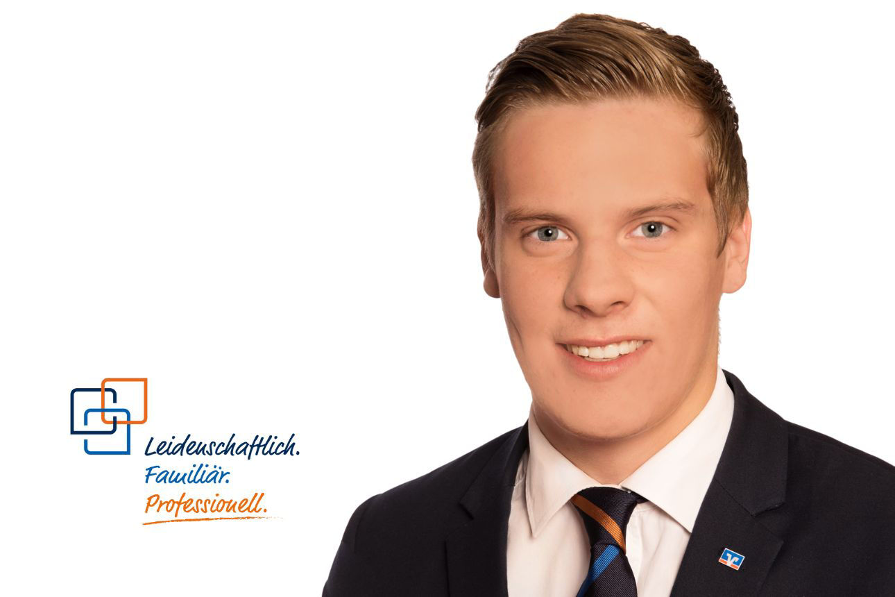 Andreas Specker, lächelnd, mit kurzen blonden Haaren und einer Krawatte in Dunkelblau und Orange gestreift.