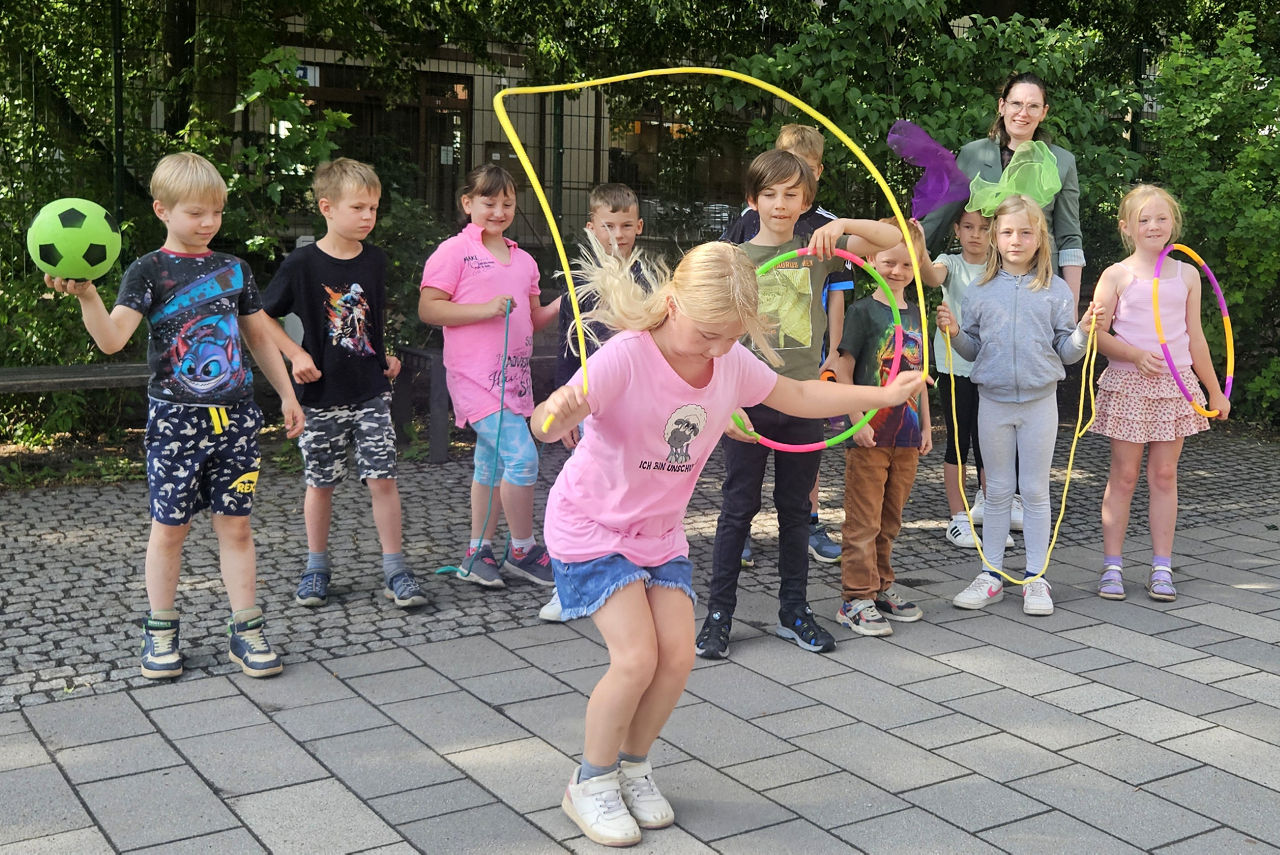 Ein Kind springt mit einem Sprungseil vor einer Gruppe von Kundern