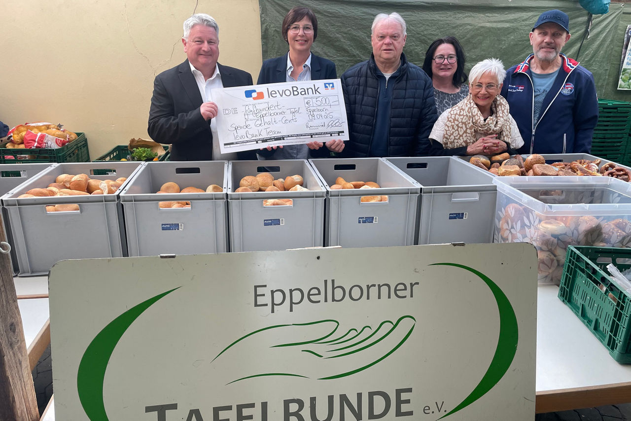 Gruppe steht vor Obstkisten und hält einen Schauscheck hoch