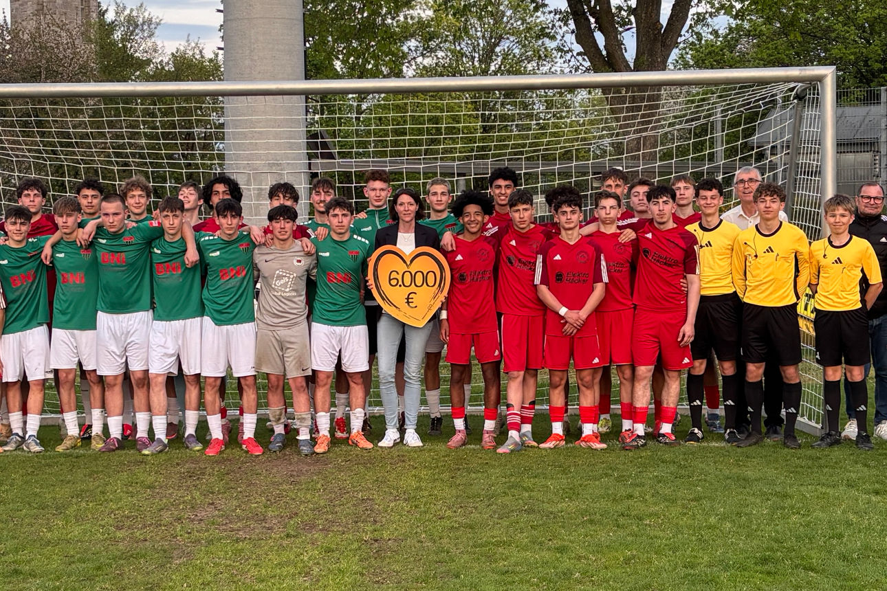 Auf dem Bild sind die Mannschaften des FC Schweinfurt 05 und die Mannschaft der Freien Turner Schweinfurt. Mittig steht die Regionalleiterin der VR-Bank, sie hält ein Spendenherz in den Händen mit Aufschrift der Spendensumme.