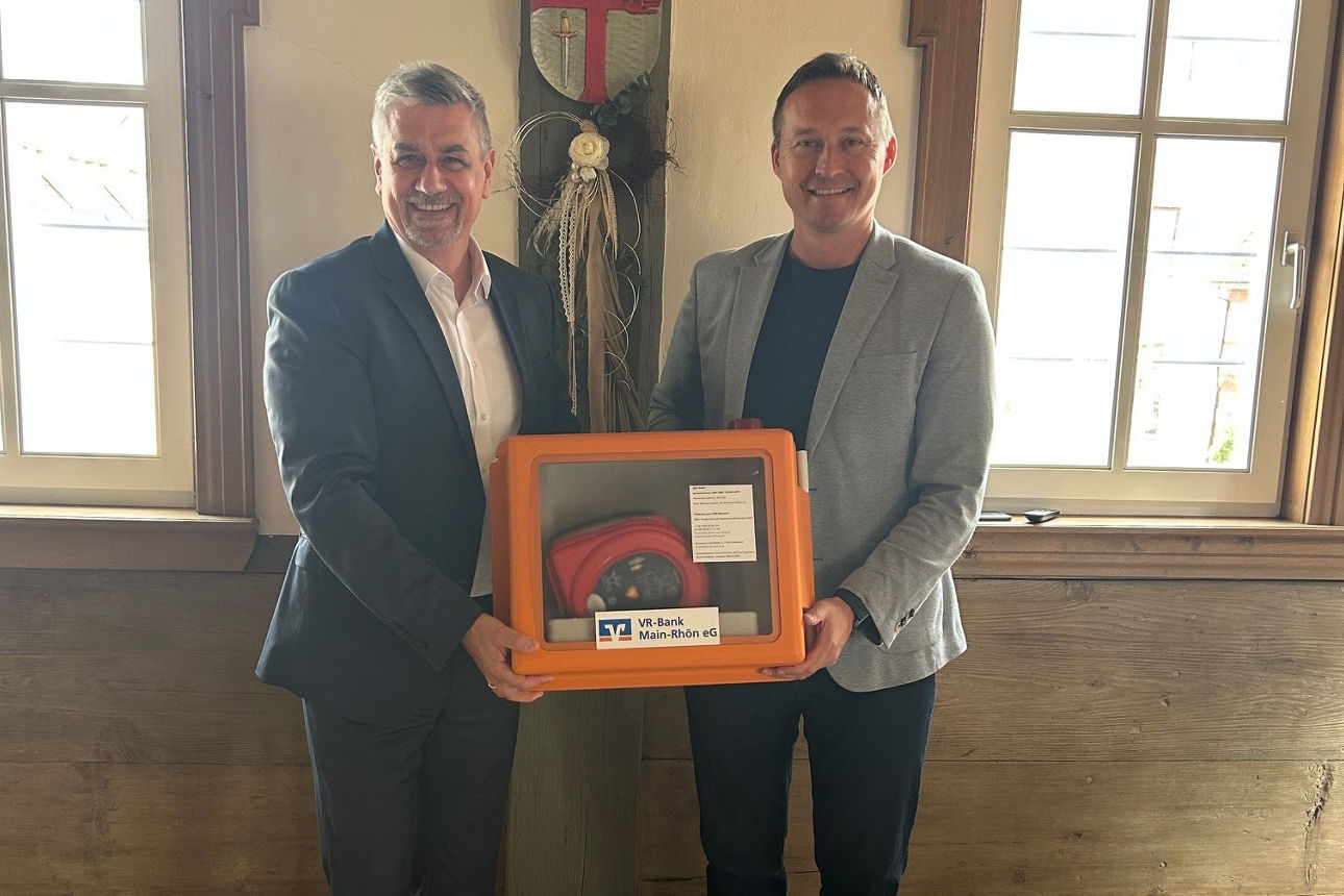 Das Bild zeigt die Übergabe des Defibrillator, der Regionalleiter der VR-Bank übergibt den Defibrillator an den Bürgermeister des Markt Stadtlauringen. 