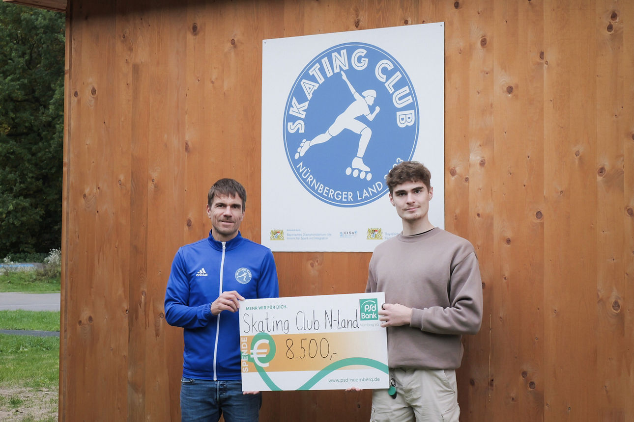 Ein Kollege der PSD Bank Nürnberg übergibt einen Spendencheck an den Skating Club Nürnberger Land