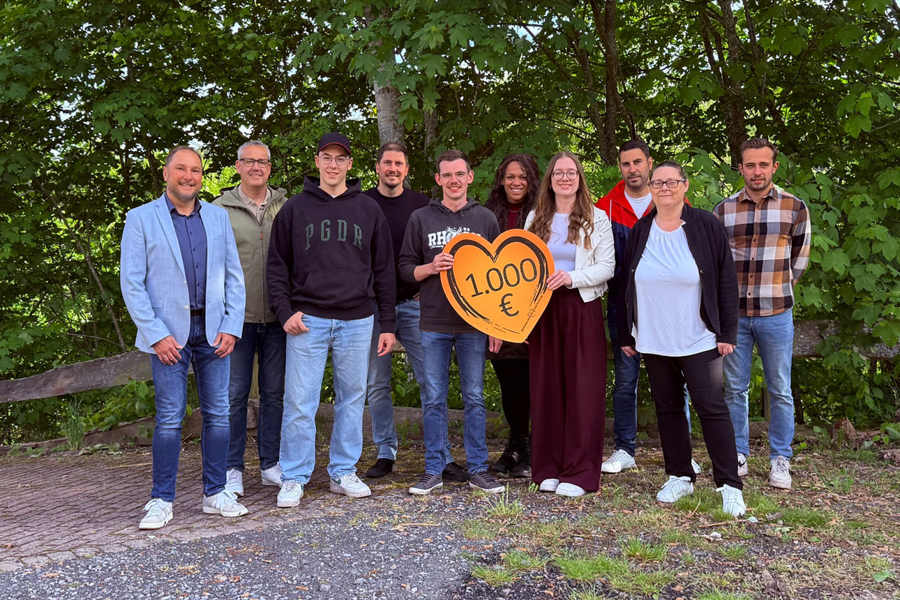 Die Filialberaterin der VR-Bank und Mitglieder des Vereinsring stehen nebeneinander im Freien vor Bäumen. In der Bildmitte halten zwei Personen ein Herz mit Aufschrift der Spendensumme in den Händen.