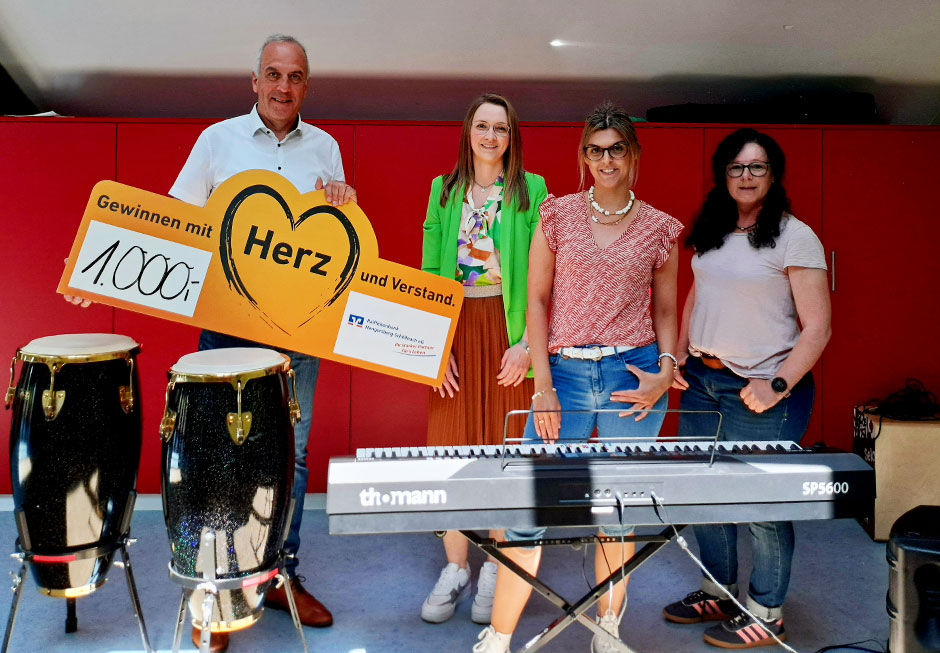 Schulleiterin mit Vertretern der Bank bei der Spendenübergabe hinter Musikinstrumenten