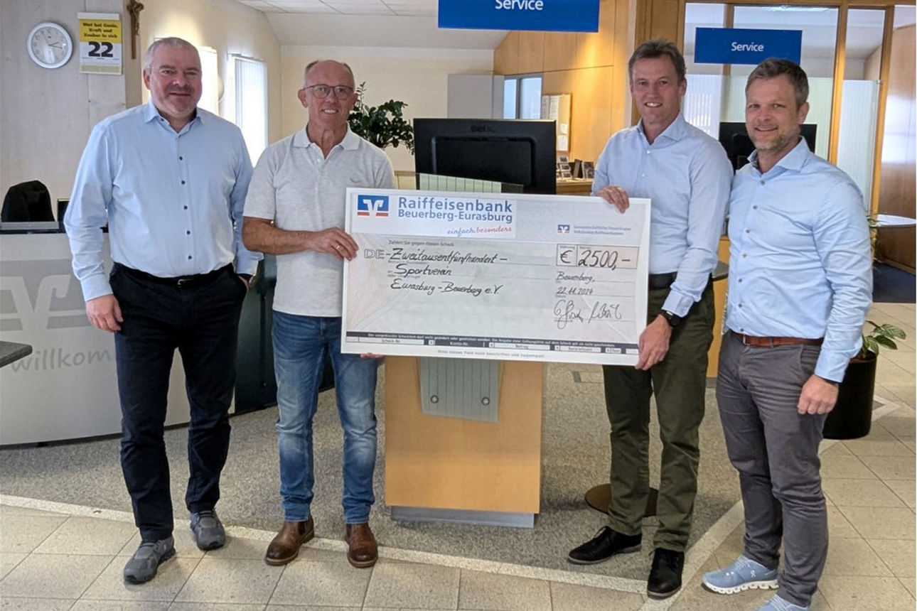 Vier Männer stehen vor einem großen Scheck über 2500 Euro von der Raiffeisenbank Beuerberg-Eurasburg