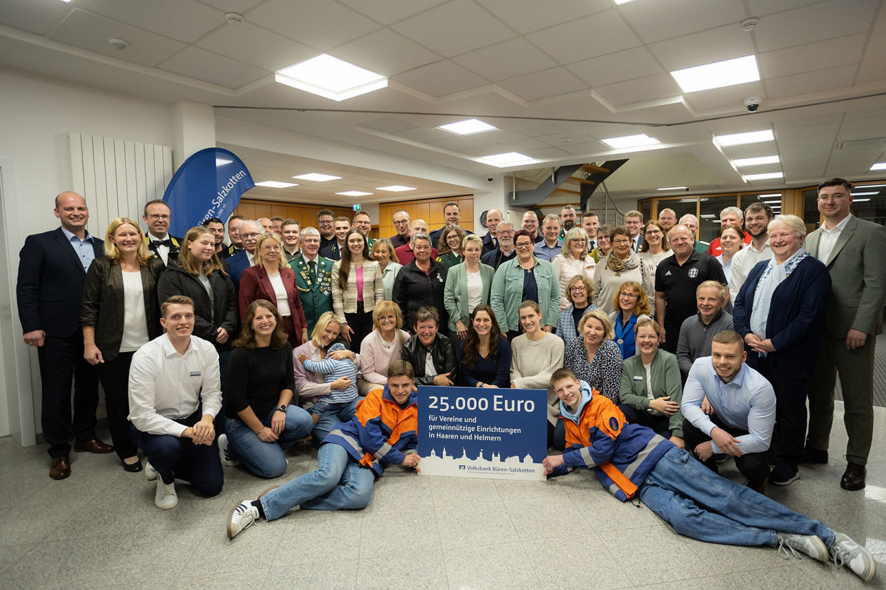 Vertreterinnen und Vertreter der Volksbank Büren-Salzkotten und der Vereine aus Haaren und Helmern stehen in der Filiale mit einem Spendenscheck.