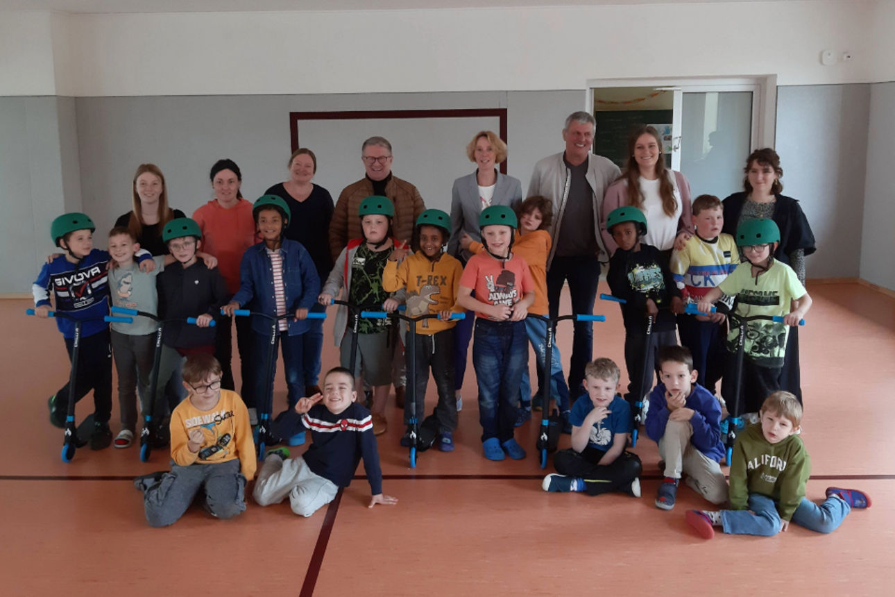 Erwachsene und Kinder halten bei der Spendenübergabe