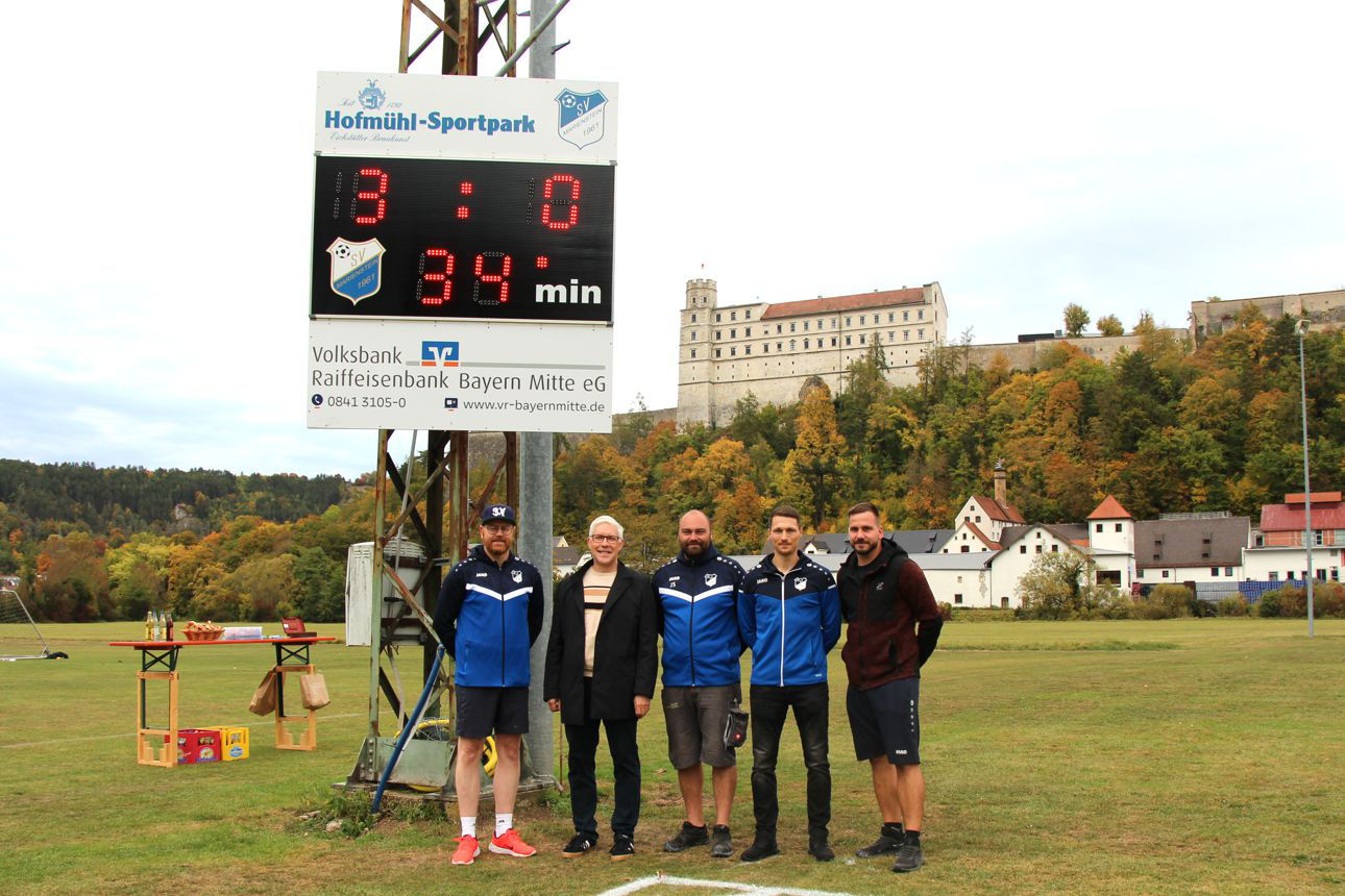 Lachende Gruppe von 5 Männern vor der neuen Anzeigentafel des SV Marienstein