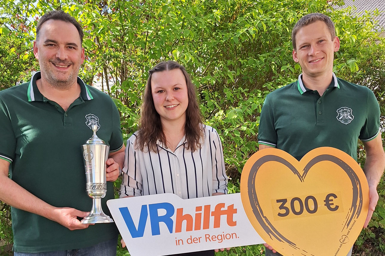 Zwei Verteter eines Schützenvereins halten zusammen mit einer Bankberaterin einen Spendenscheck in die Kamera.