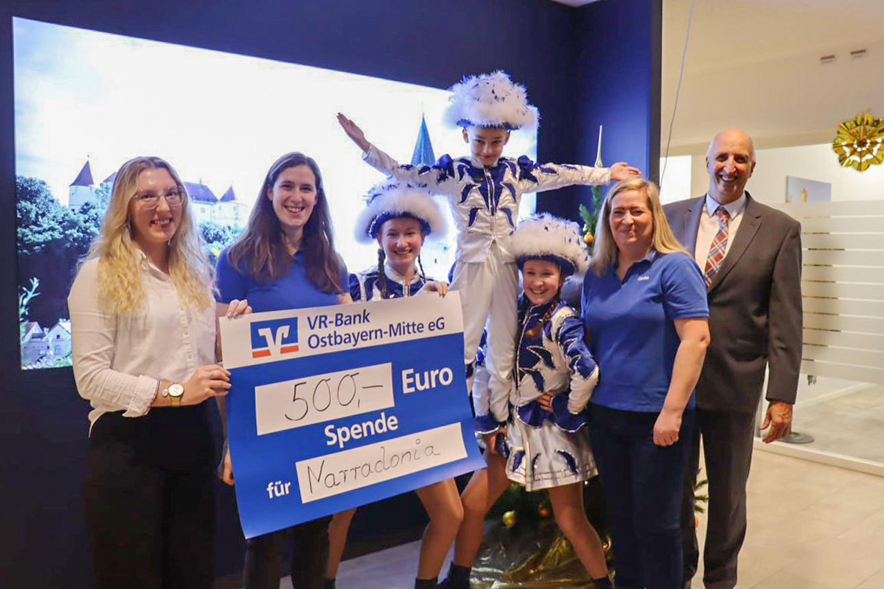 Ein Mann und vier Frauen lächeln in die Kamera und halten einen Spendenschein hoch