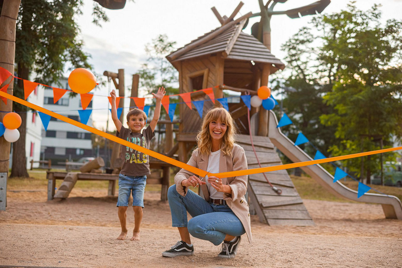 Frau beim Durchschneiden eines Bandes zur Eröffnung eines Spielplatzes
