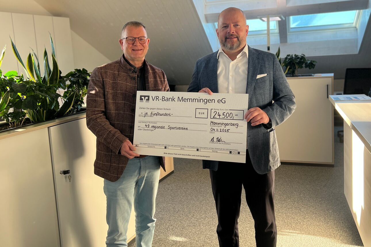 Vorstände stehen mit Spendenscheck in der Hand im Büro