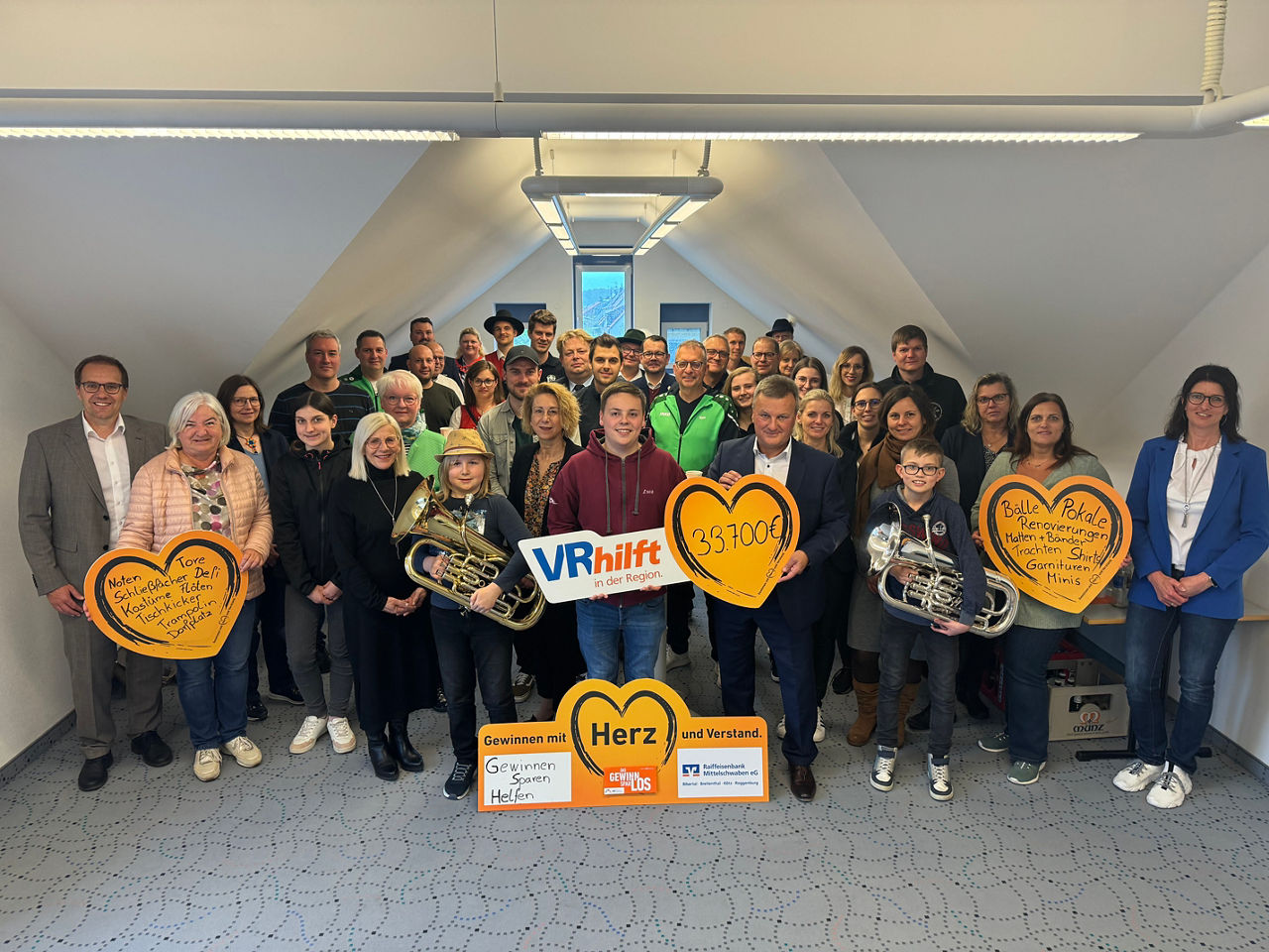 Eine Gruppe von Menschen, die für ein Foto posieren, einige halten orangefarbene Pappherzen mit Aufschriften
