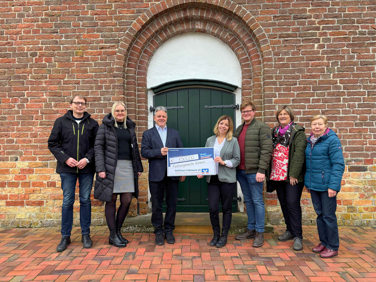 Sieben Personen bei einer Scheckübergabe