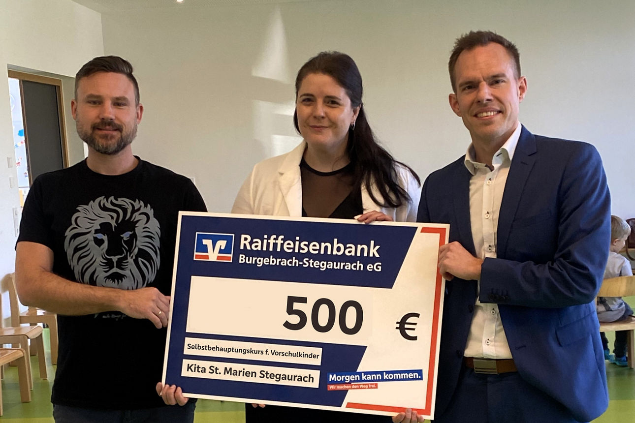 Drei Personen halten einen 500‑Euro‑Scheck für die Kita St. Marien.