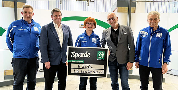 5 Personen stehen zusammen und eine Frau in der Mitte hält einen großen Spendencheck in Ihren Händen