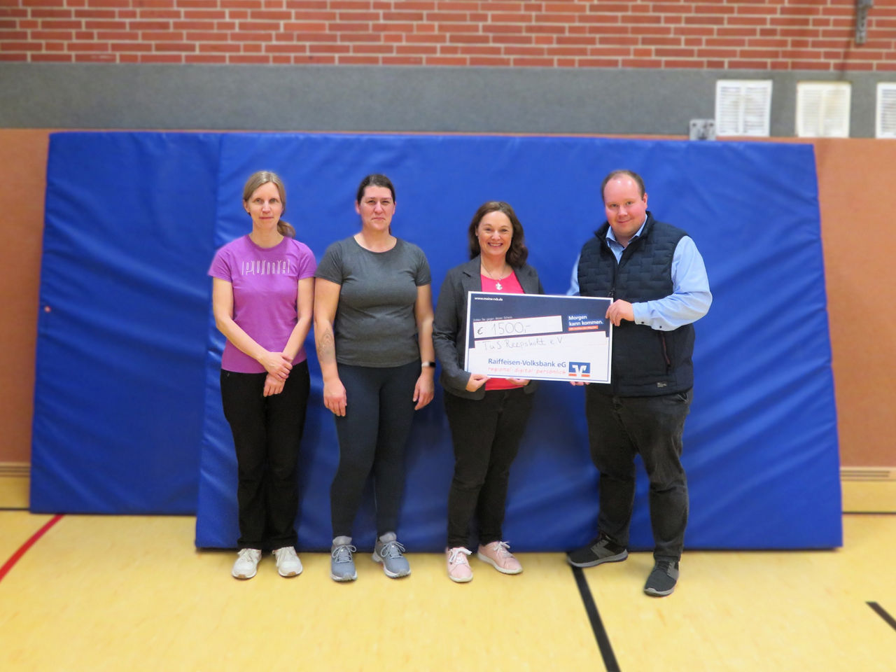 Vier Personen bei einer Spendenübergabe