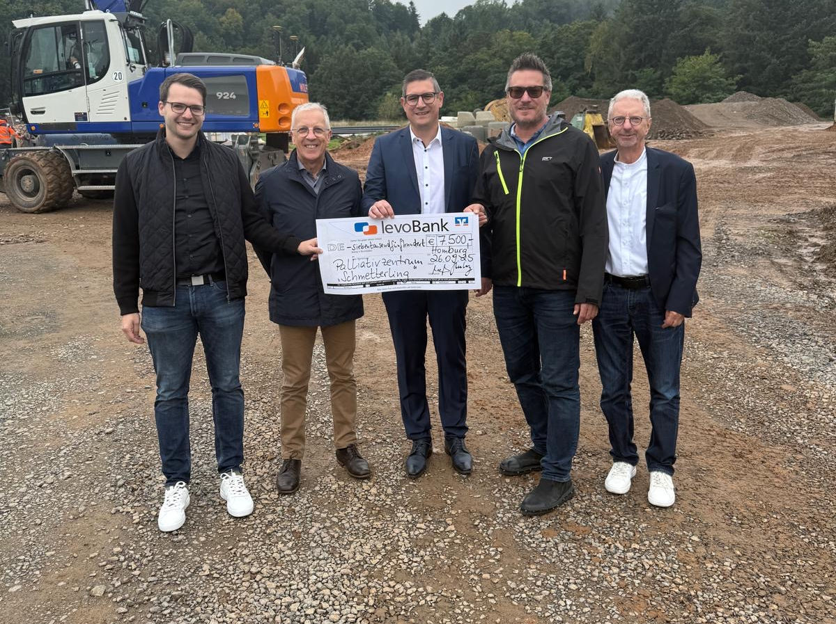 Gruppe steht auf Baustelle und hält einen Schauscheck