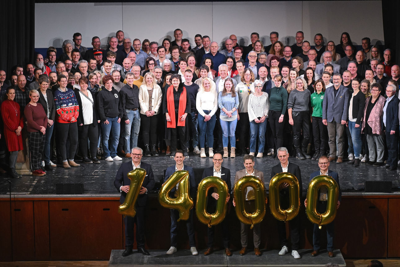 Gruppenfoto der Spendenempfänger im Vordergrund halten 6 Personen die Zahl 140.000