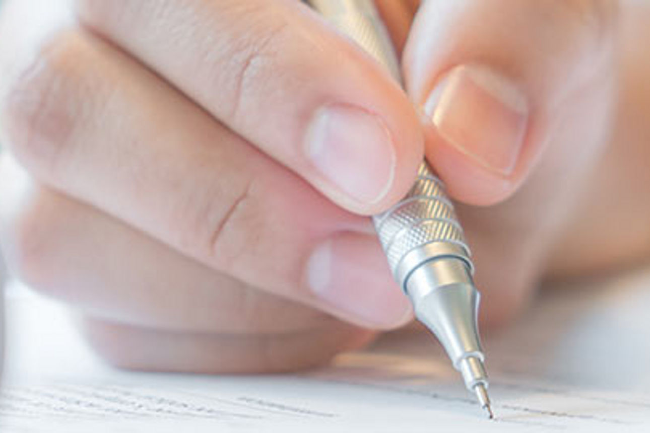 Nahaufnahme einer Hand, die akribisch Dokumente ausfüllt.