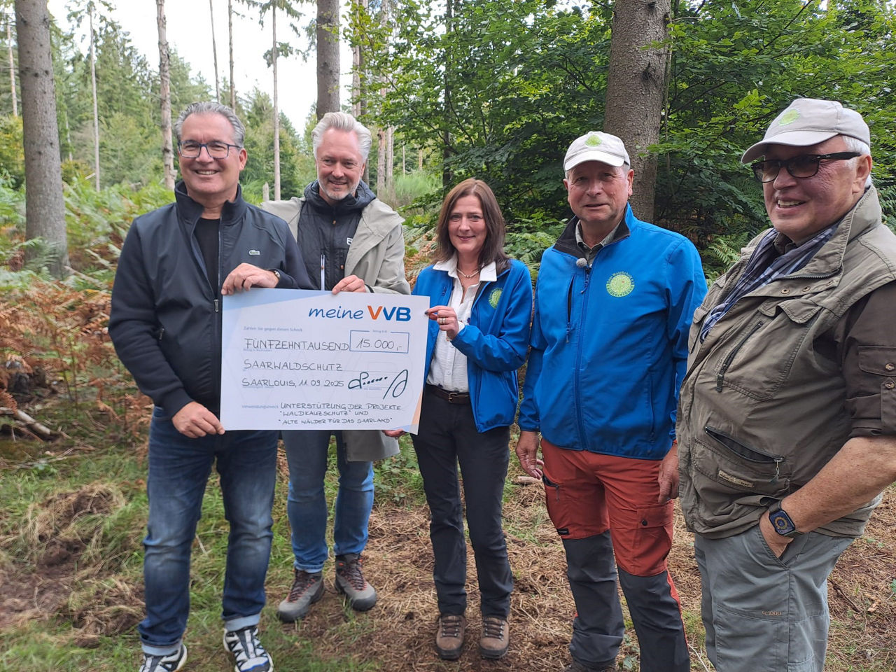 4 Männer und eine Frau im Wald bei einer Spendenscheckübergabe