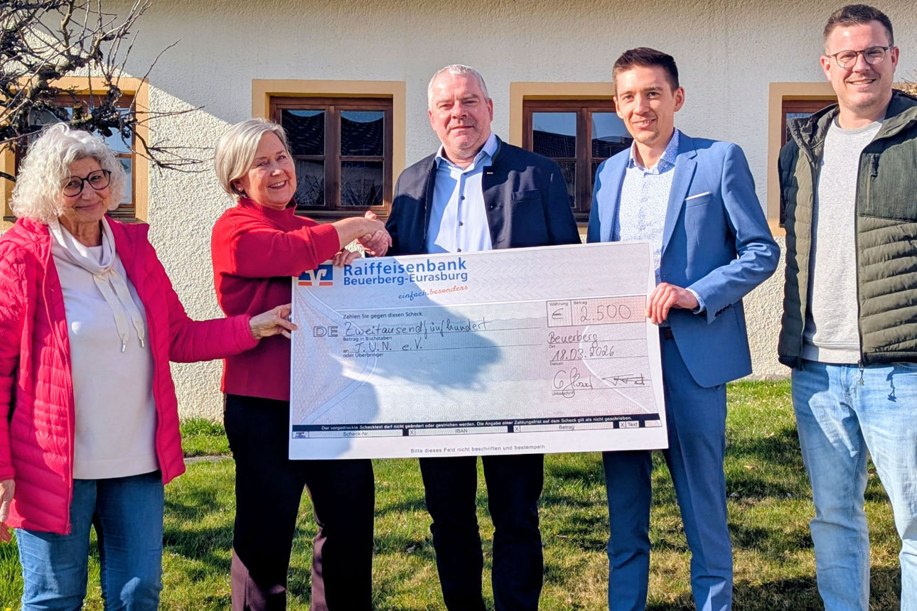 fünf Personen stehen vor einem Haus und halten einen symbolischen Scheck in den Händen