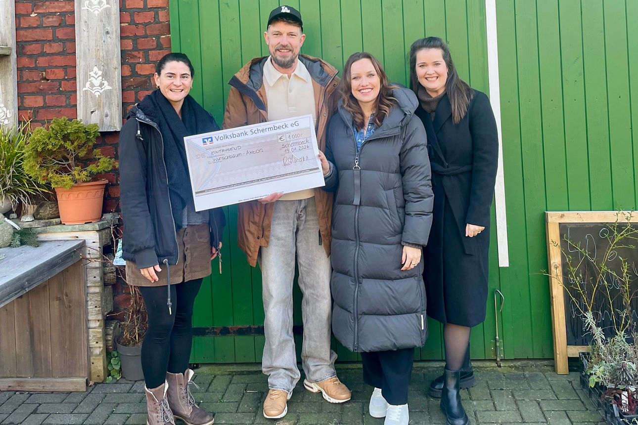 Spendenübergabe vor einem grünen Scheunentor mit drei Frauen und Michael Rittmann