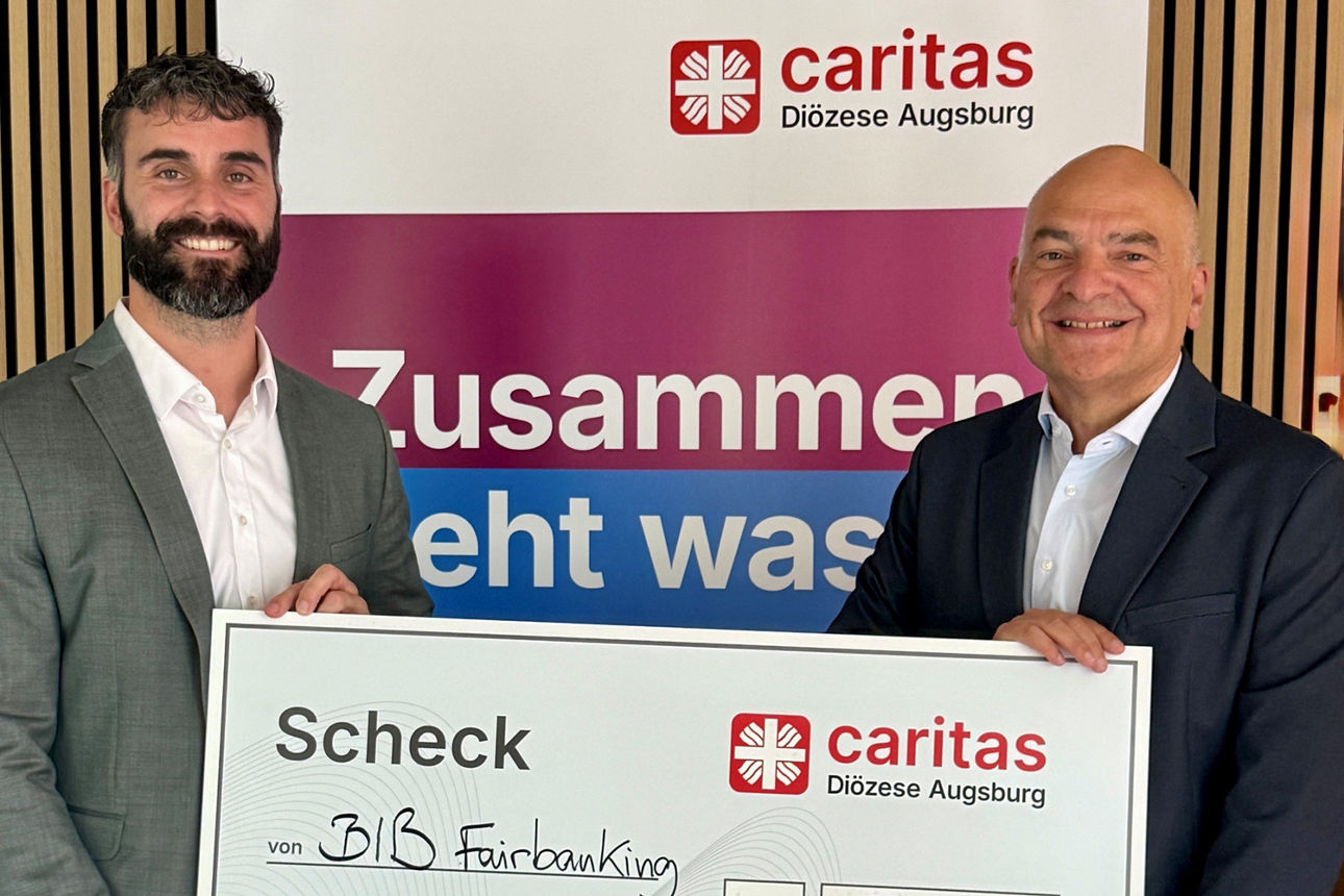 Frederik Hornung, Regionaldirektor der BIB, überreicht einen Scheck an die Caritas Augsburg
