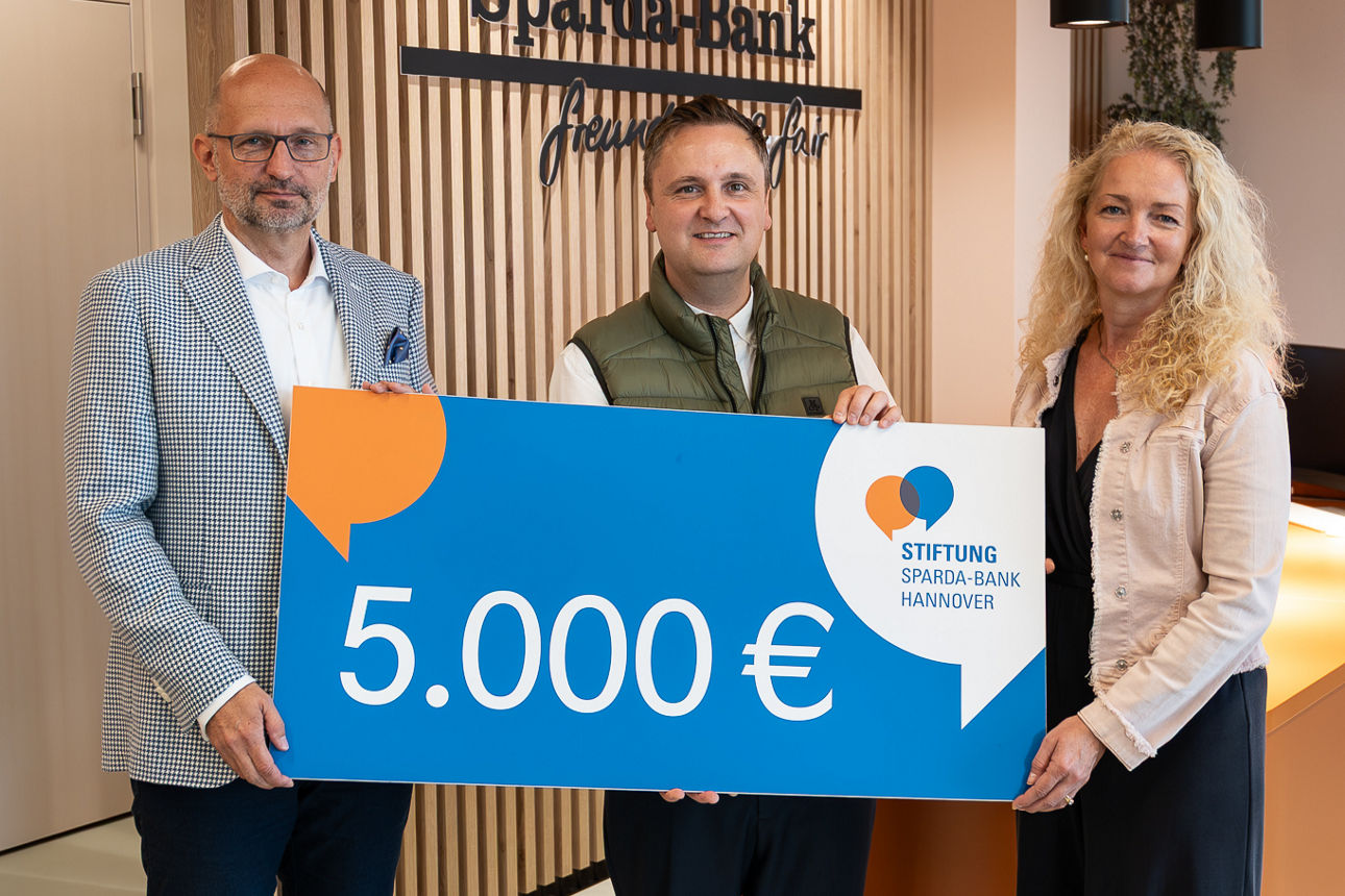Drei Personen halten einen Spendenscheck im Wert von 5.000 Euro in den Händen